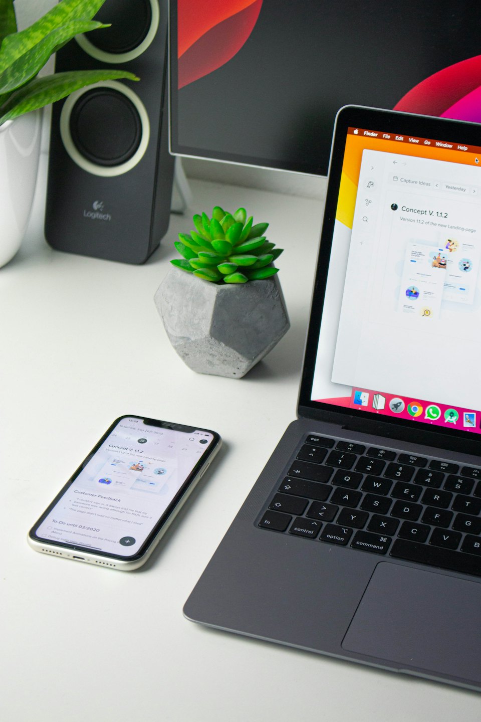 ラップトップ、電話、スピーカー、植物のあるモダンなデスク。